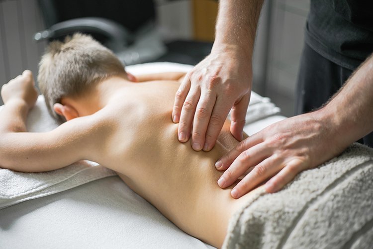 young boy receiving massage from his therapist