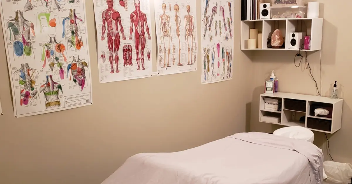 Got Knots treatment room with a massage table, face cradle and anatomy charts on the wall