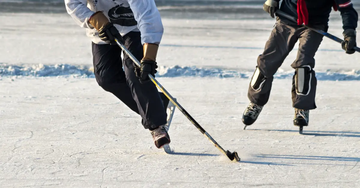 Two adults playing pond hockey on an outdoor rink